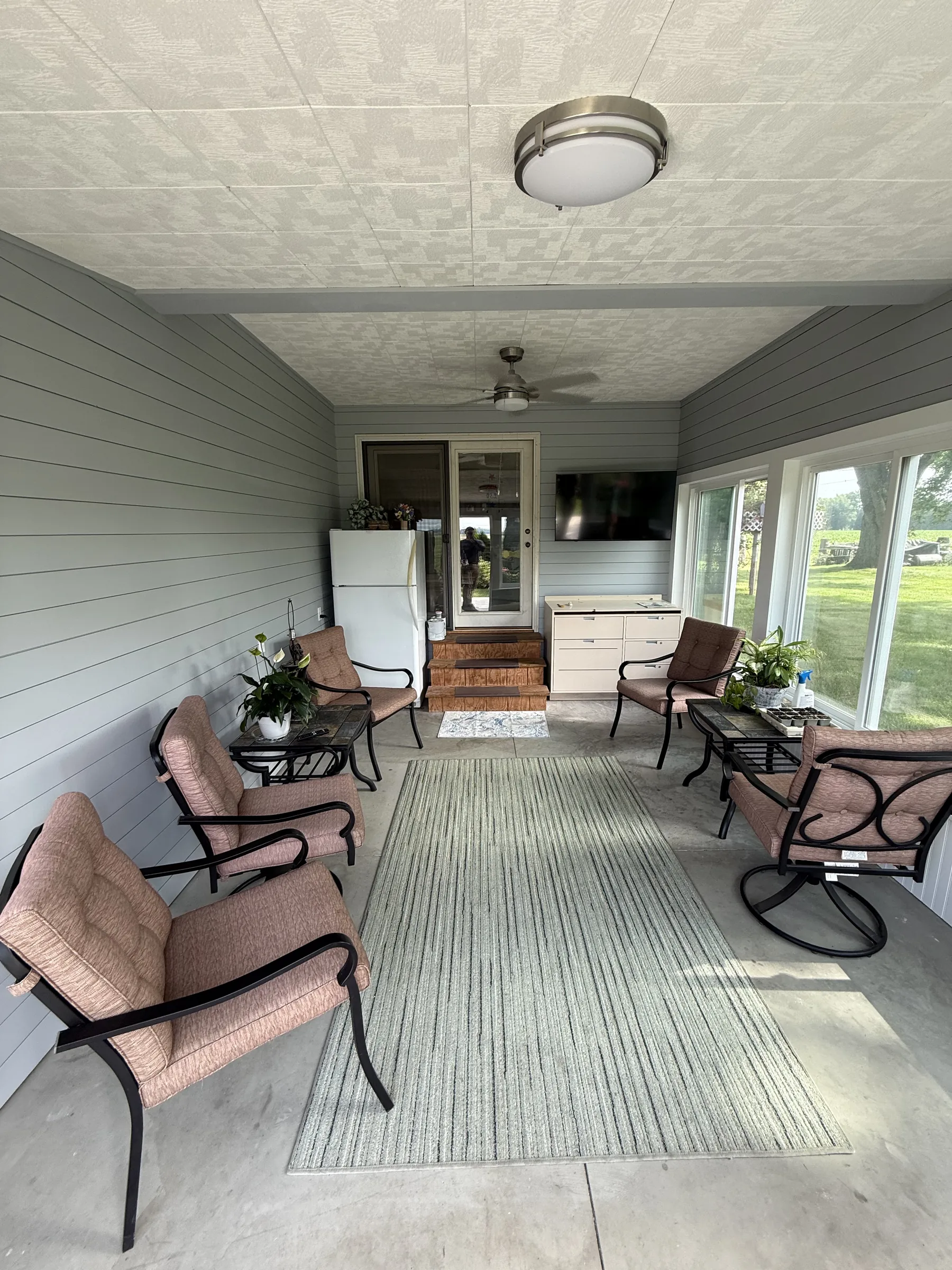 Finished sunroom remodel with shiplap walls and seating overlooking the yard